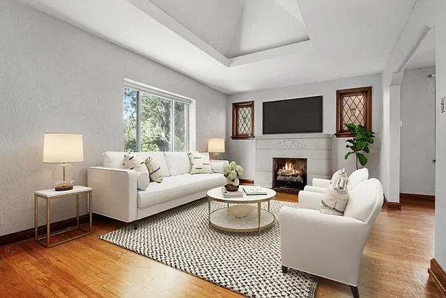 The sunlit living room features a vaulted ceiling and a decorative fireplace.