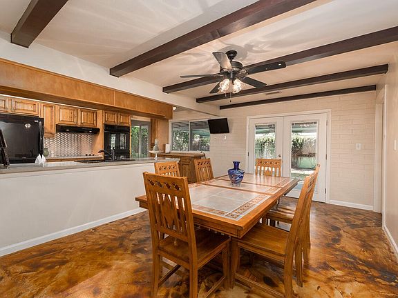 Dining room with beamed ceiling, ceiling fan and raised cabi