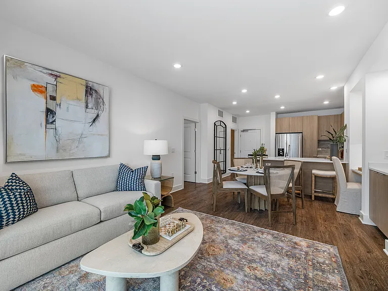 Inviting open-plan living area with a modern kitchen, elegant dining set, and chic lounge featuring contemporary artwork and stylish decor.