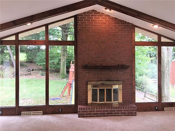 Fantastic family room with vaulted beamed ceilings, endless windows and fireplace looking out on the side yard.