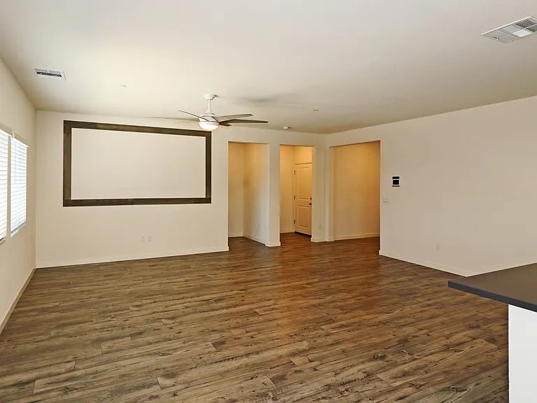 Great room as seen from the kitchen and dining area. The left doorway at the far end leads to the Primary bedroom. The middle doorway leads to the interior garage door.