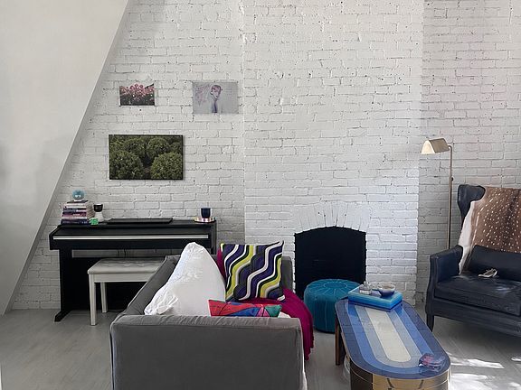 Beautiful original brickwork, a decorative fireplace, piano, and flexible seating create a character-filled living space that feels both stylish and comfortable.