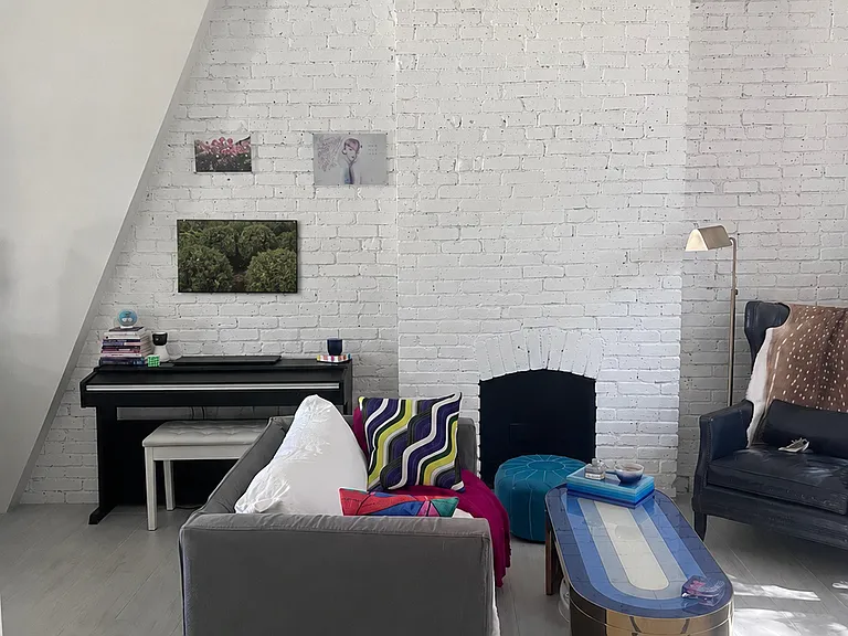 Beautiful original brickwork, a decorative fireplace, piano, and flexible seating create a character-filled living space that feels both stylish and comfortable.