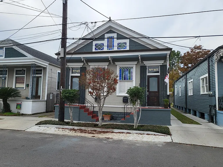 The house features functioning shutters on doors and windows. Sweet olive trees and a Japanese maple line the front of the home.