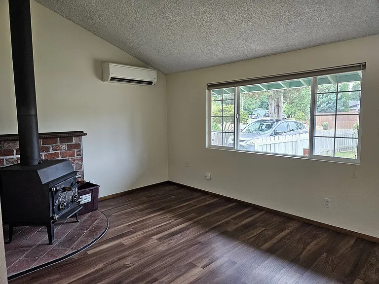 Main floor living room looking SW at wood stove, heat pump and window