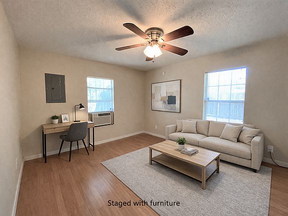 Light filled living room with wood plank flooring and ceiling fan