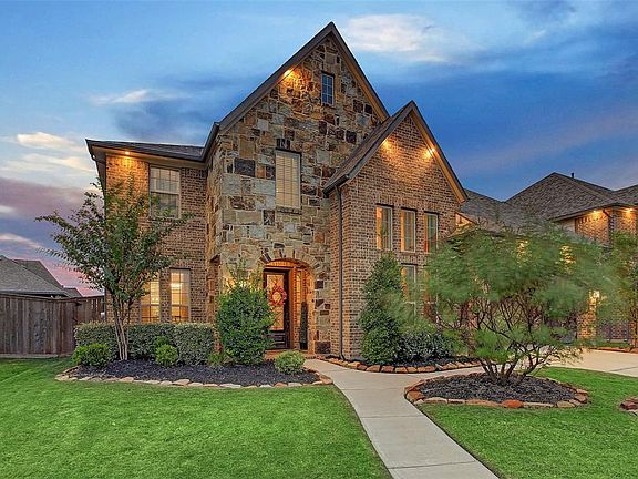 Thoughtful upgrades on exterior as well as interior. Note the brilliant recessed soffit lighting, lush landscaping, and garage portico extension.