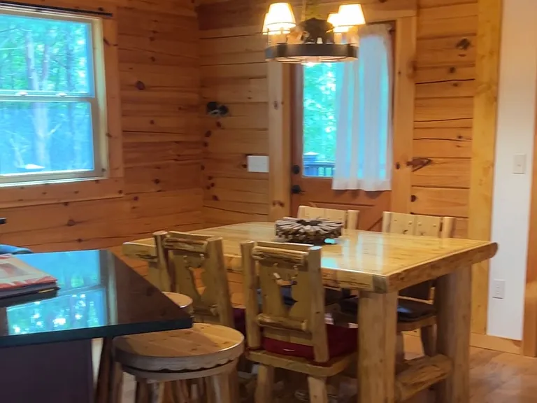 Dining table is log and has 4 chairs with deer head carving on backs. 
The washer and dryer are side by side in this area inside a closet (not visible unless you open closet doors).