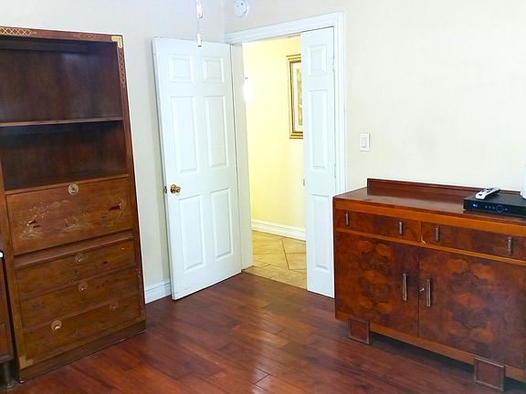 Locking entry door leads to hallway with bathroom, laundry room, and door opening to back yard with koi pond and swimming pool. The large refrigerator is shown on right side of this photo