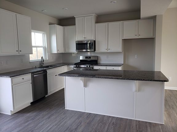 granite kitchen counters, kitchen island with counter seating area, dishwasher, electric stove, microwave included