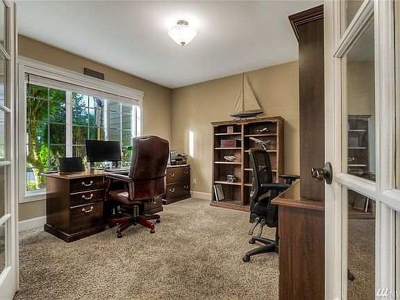 Dramatic two story entry with refinished hardwoods, new wrought iron stair railing and updated lighting. The office is located behind the french doors. Note the custom 5 1/4" baseboards that have been installed throughout the home, a sign of the great care taken in regards to the finishes in the home. 