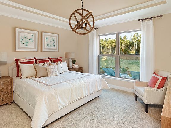 Bright and spacious owner s suite with tray ceiling, decorative lighting and views of the rear yard.