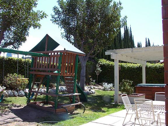 Private backyard with covered patio, hot tub, and swing set.