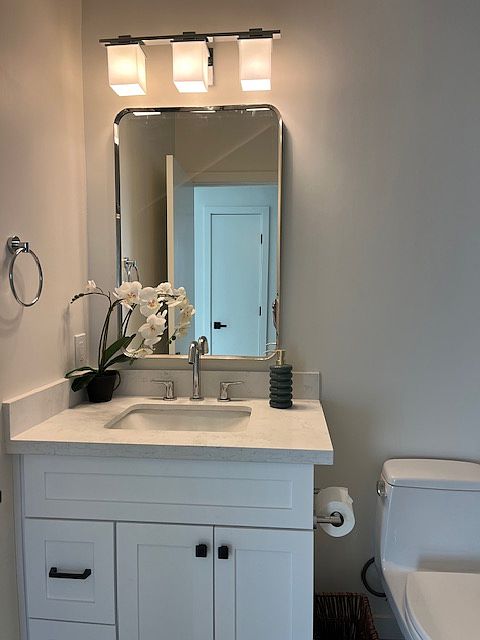 Beautiful new bathroom with white shaker cabinetry. quartz counter top, LED lighting, glass tub/shower enclosure with tile tub/shower surround and waterfall design accent tiles.
