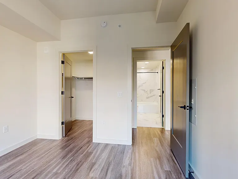 Spacious apartment bedroom with large closet and wood-style flooring.