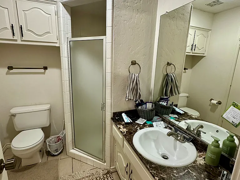 Bathroom featuring patterned tile flooring, vanity, toilet, and shower stall