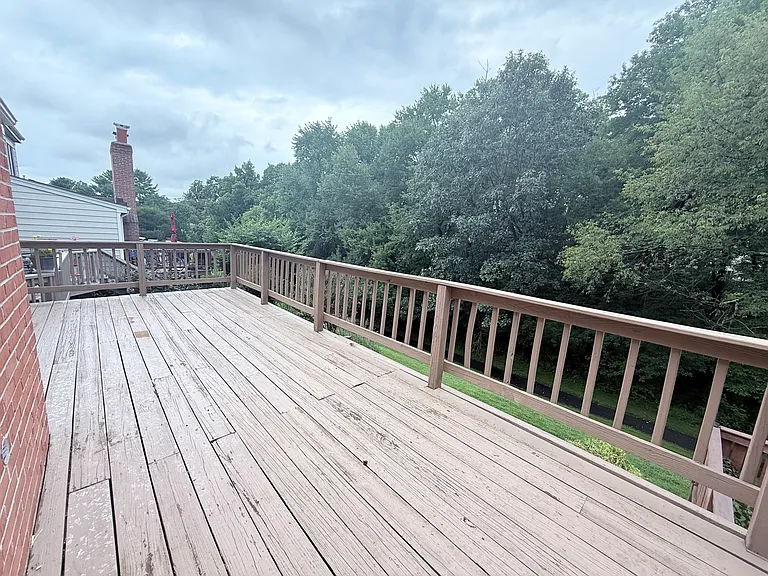 Large wooden deck above a wall out brick patio