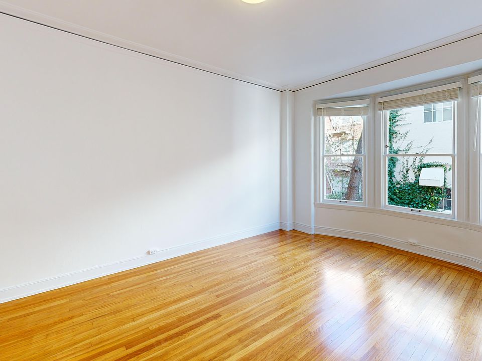 Spacious, sunlit room with hardwood floors and large bay windows