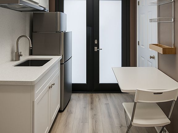 Sleek kitchenette with stainless appliances, ample storage, and foldable table set.