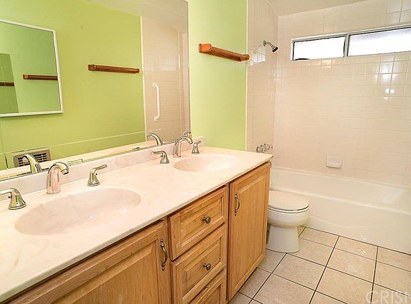 The nicely updated full hallway bathroom with dual sink vanity and shower over tub.