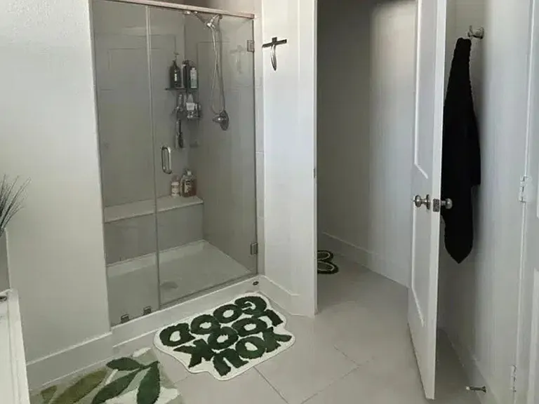 Bathroom features a glass-enclosed shower, tile flooring, and a vanity with ample counter space and storage.