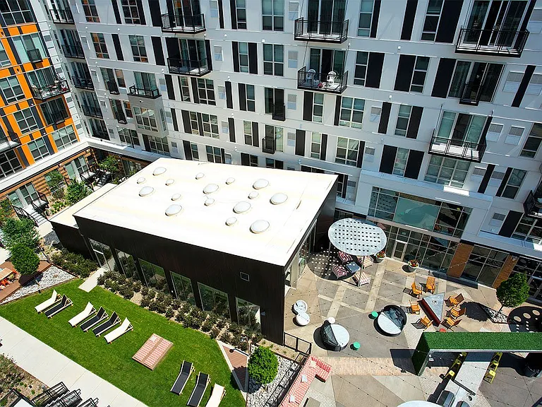 A modern building with a white roof and a green lawn in front.