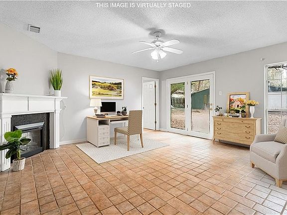 Office space with a ceiling fan, visible vents, a glass covered fireplace, and a textured ceiling