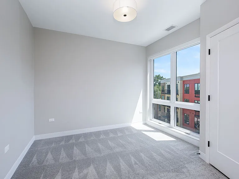 Bedroom with floor to ceiling windows that feature blackout rolling shades