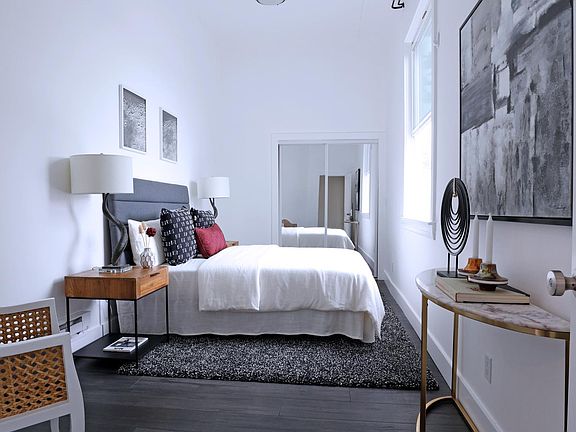 Master bedroom with mirrored doors on closet and extra-high, dramatic ceilings.