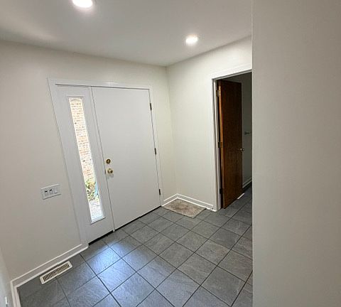 Front Foyer with access to powder room, living area, and kitchen