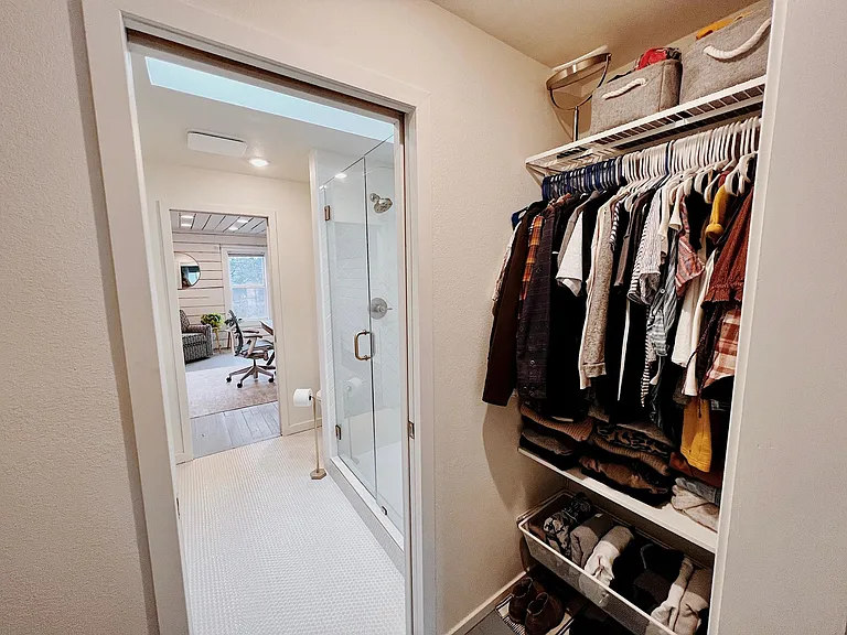 Primary bedroom closet looking into bathroom