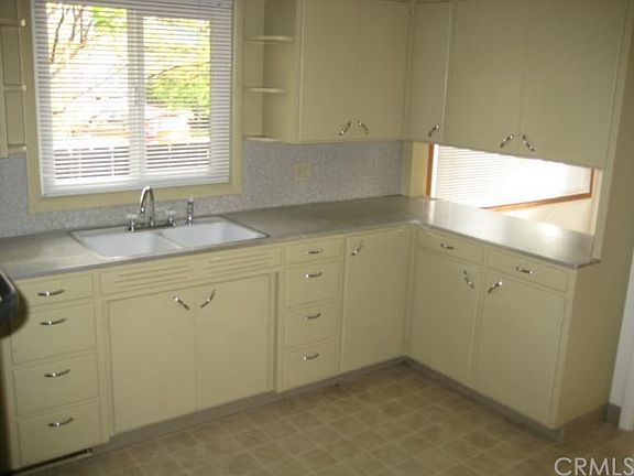 Vintage kitchen with wood cabinets and formica counters.  Double sink.
