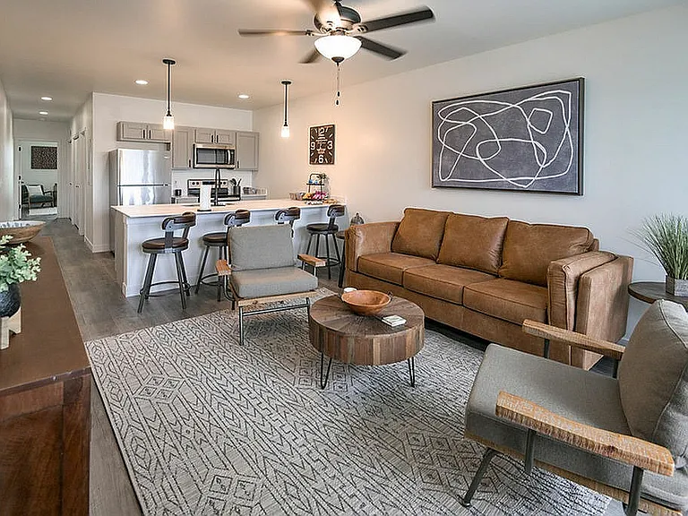 Modern open-plan living space with cozy leather sofa, sleek kitchen, and stylish bar seating, perfect for entertaining.
