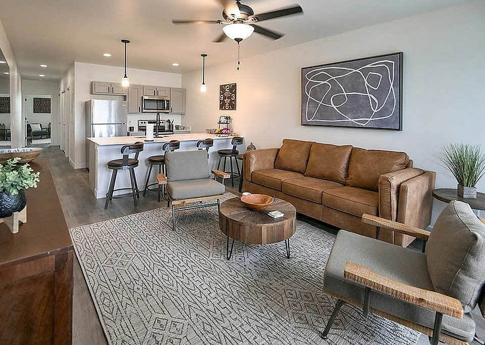 Modern open-plan living space with cozy leather sofa, sleek kitchen, and stylish bar seating, perfect for entertaining.