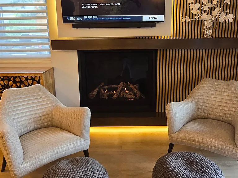 New remote-controlled fireplace with lighted log set and temperature-controlled heat. Custom designed back-lit TV panel, wood mantel and bottom-lit hearth. 2 huge push-to-open top and bottom storage compartments behind fluted wall panels
