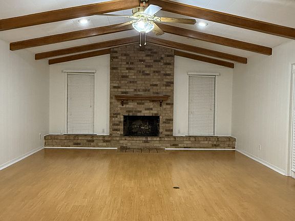 Spacious family room with vaulted ceiling and wood beams and fireplace, also has electric plug in floor for lamps or other electronics.