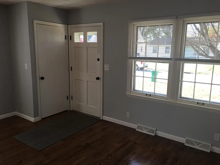 Front entrance door and living area, nice windows and great light, hall/coat closet, ceiling fan.