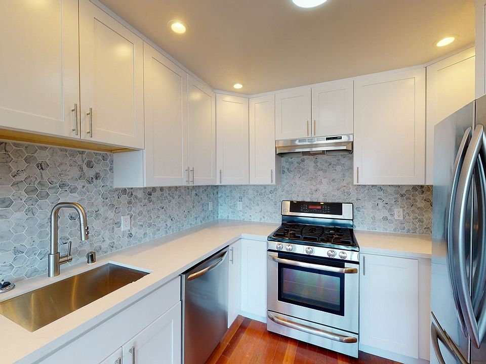Kitchen with multiple cabinets, refrigerator, stove, and sink