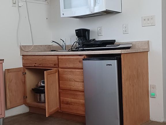 Kitchen area includes microwave, counter top induction stoves (2- 1 small and 1 large), mini-beverage fridge, and induction cookware. A/C unit in kitchen/livingroom area, as well as a ceiling fan. In-wall heating unit. Floors are sealed concrete.