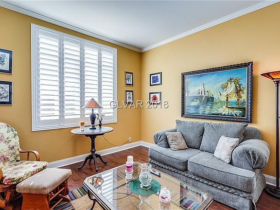 Living room with wood laminate floors, plantation shutters and crown molding...
