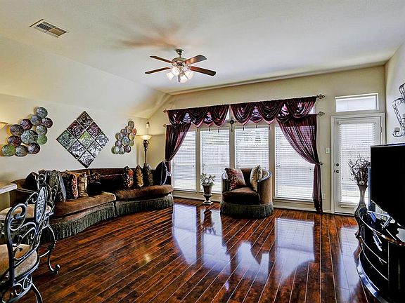Family room has hardwood floors, ceiling fan and a wall of four windows with transoms and glass door that leads to the patio,