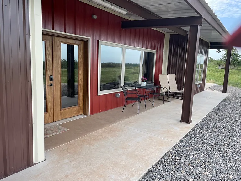 Front double door and large window. Outside patio area with patio table and chairs.