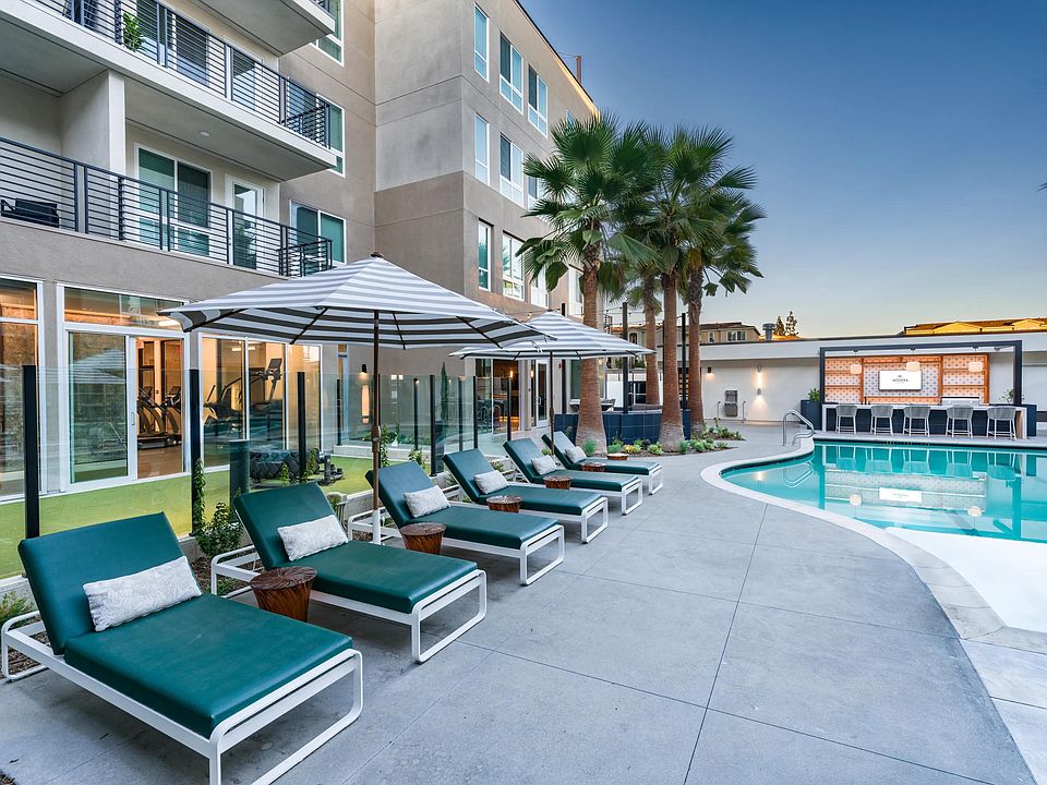 Relax by the resort-style pool at Modera Pomona, featuring a lounge area, seating, and palm trees.