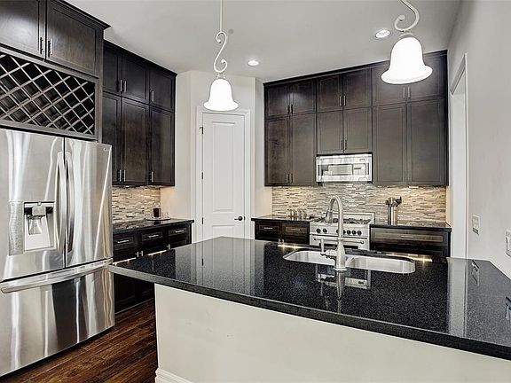 Beautiful and functional kitchen has custom cabinets with contemporary hardware and wine storage, stylish tile backsplash, breakfast bar seating, and an upscale Bertazzoni range.