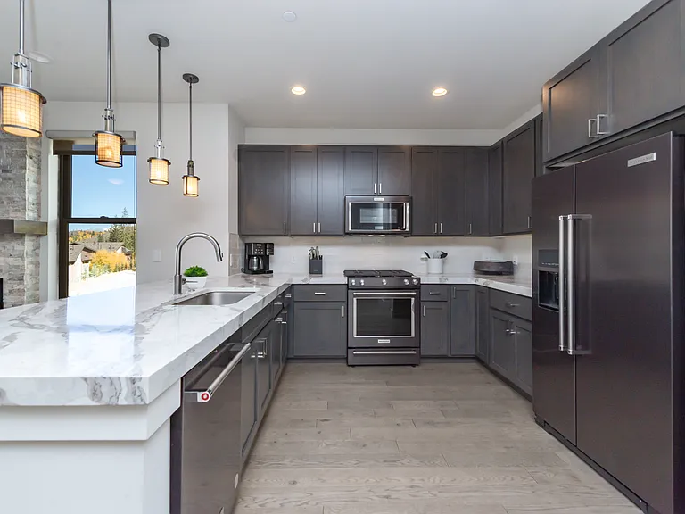 Upgraded 3" quartz countertops and sleek black stainless steel appliances create a modern, high-end kitchen aesthetic.