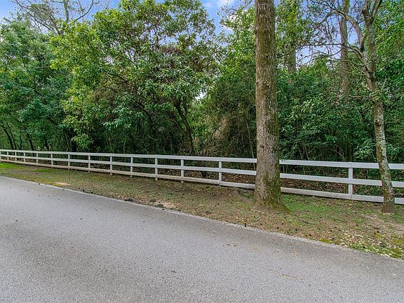 White fence lines the front of this large wooded lot