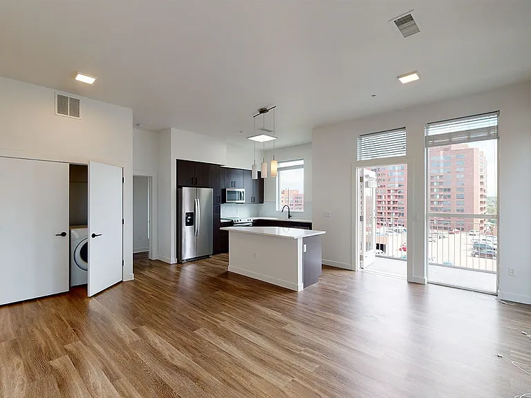 Apartment kitchen with stainless steel appliances, dining and living room with wood-style flooring and patio or balcony.