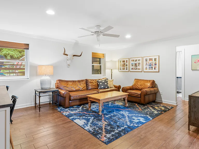 Second living room with two desk spaces, comfortable leather couch and lounge chair, Smart TV, and a ceiling fan. Perfect spot for movie night.
