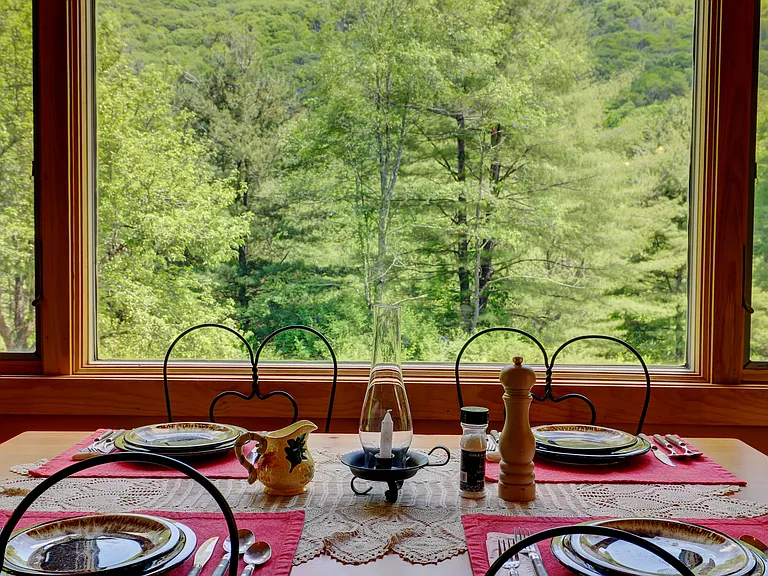 Dining Area with picture window with casement windows on each side and late springtime view of the forest.