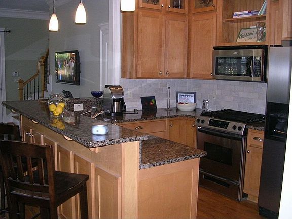 The kitchen offers plenty of cabinet and counter space, stainless steel appliances, pendant lighting and granite counters.